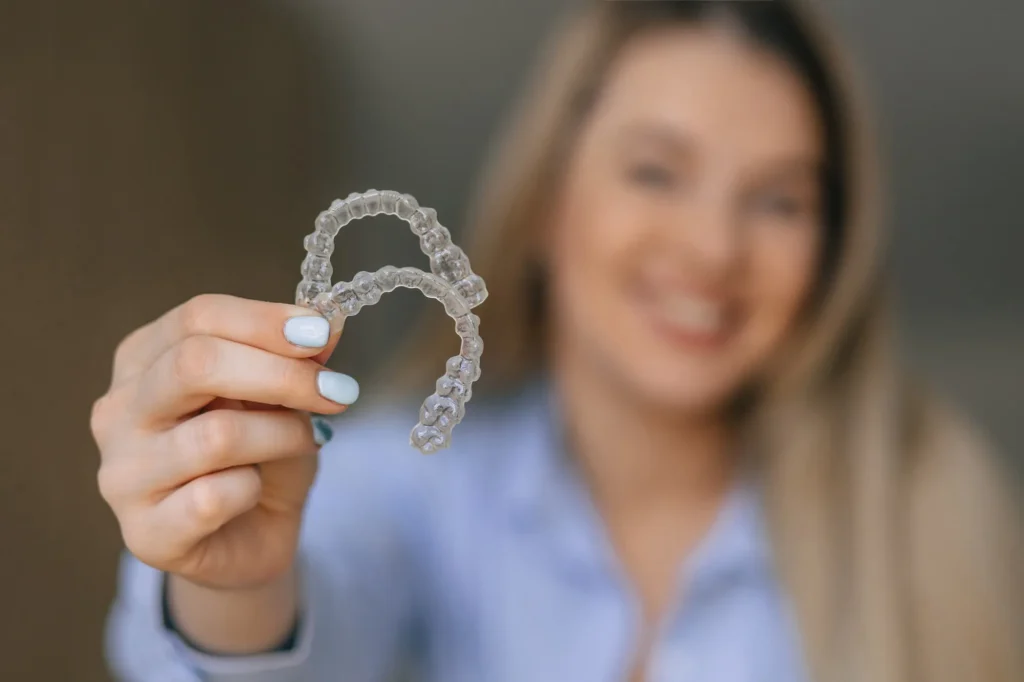 smiling while holding her clear aligners athens ga
